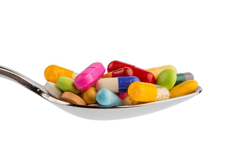 Lots of colorful tablets on a spoon. Symbolic photo for tablet addiction and misuse of medicines, Austria