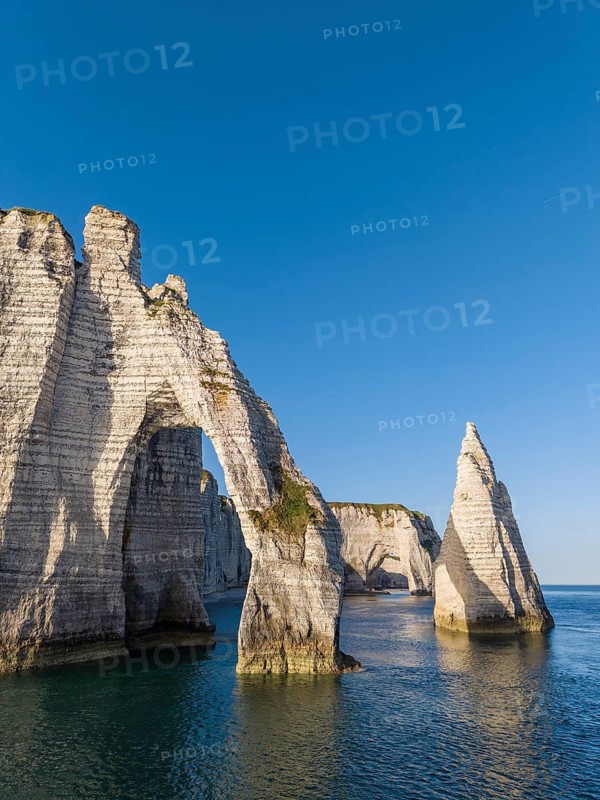 Aerial view of the Porte d'Aval rock formation with the free-standing Aiguille d'Étretat rock pin in the morning sun, well-known sights and natural beauty on the chalk coast, behind it the La Manneporte rock gate, Étretat, Alabaster Coast, La Côte d'Albâtre, chalk cliffs, English Channel, Seine-Maritime, Normandy, France