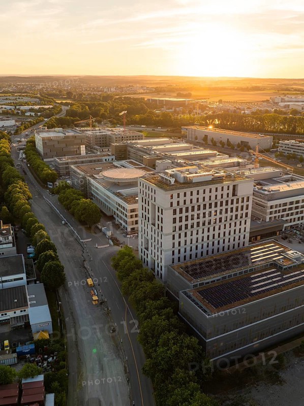 Building and street in an urban area at sunset, lined with trees, new hospital building, Böblingen airfield, Germany