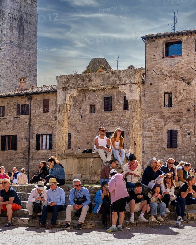 Tourists around the market square with old fountain and other sights in San Gimignano, Tuscany, Italy