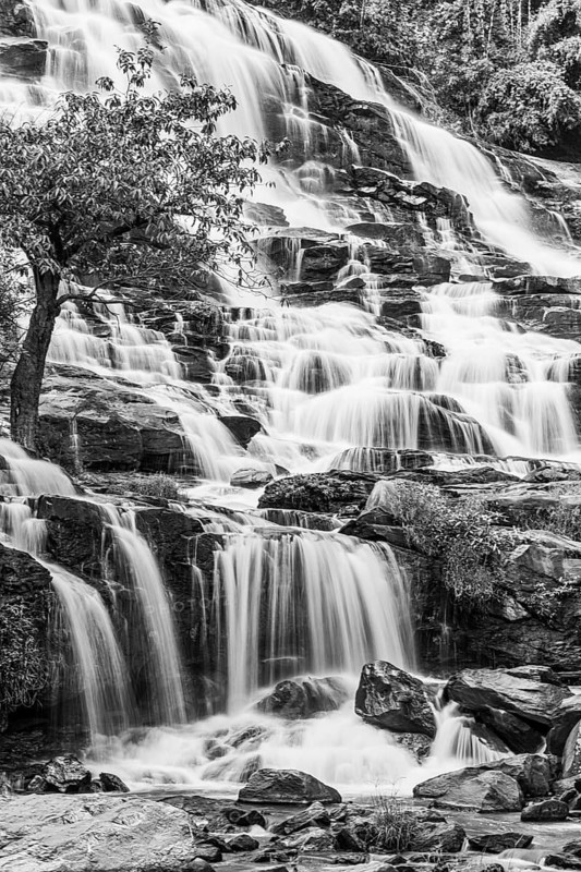 Mae Ya waterfall with cascading flowing water framed by lush tropical vegetation, black and white photo, near Doi Inthanon National Park, Chiang Mai Province, Thailand