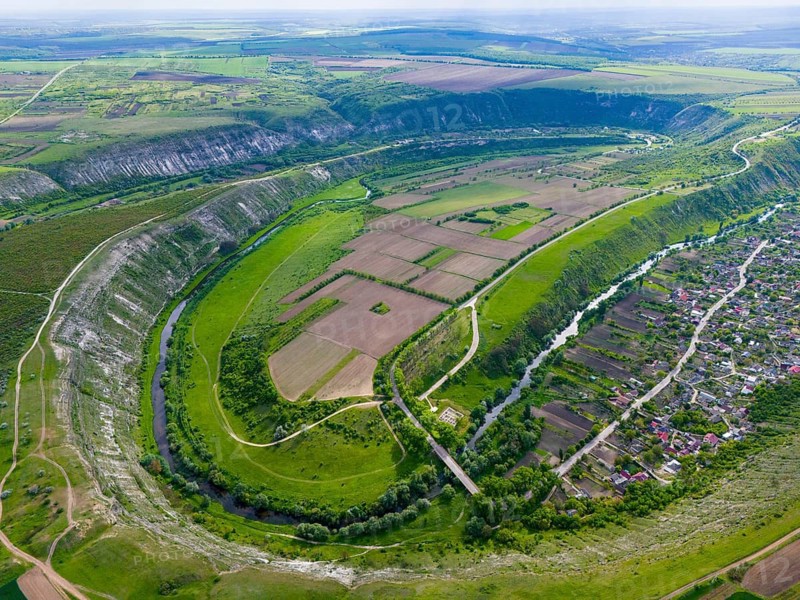 A vast, green landscape with a river flowing through fields and hills, viewed from the air, aerial view, Raut, Raut river loops, view of Trebujeni, Old Orhei, Orheiul Vechi, archaeological site, protected landscape area, Orhei district, Republic of Moldova, Moldova