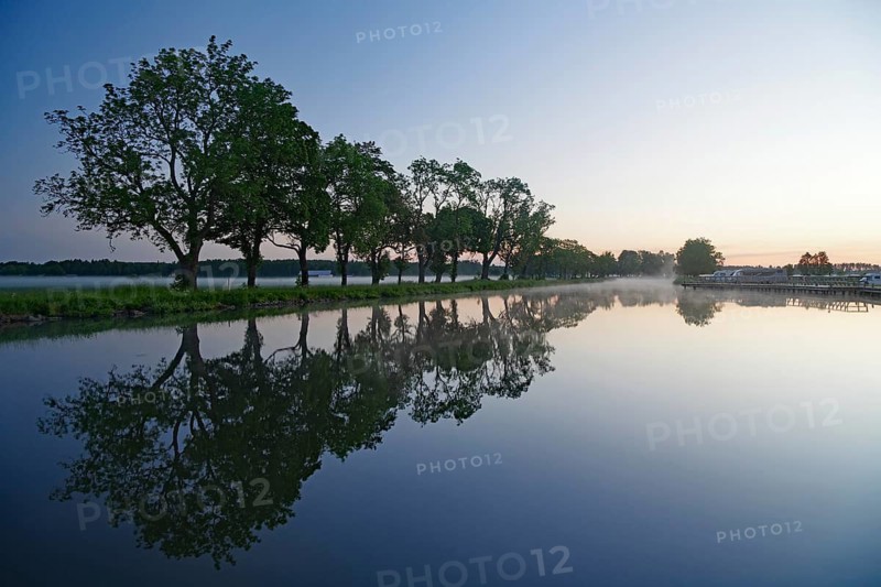 Trees reflecting on the canal in still water at sunrise, Göta Canal, Töraboda, Västra Götalands län, Sweden