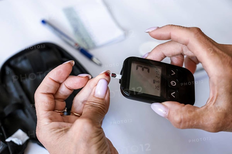 Close-up of female hands inserting a test strip into a blood glucose meter before diabetes testing. Home monitoring, endocrinology, healthcare technology and chronic disease prevention concept