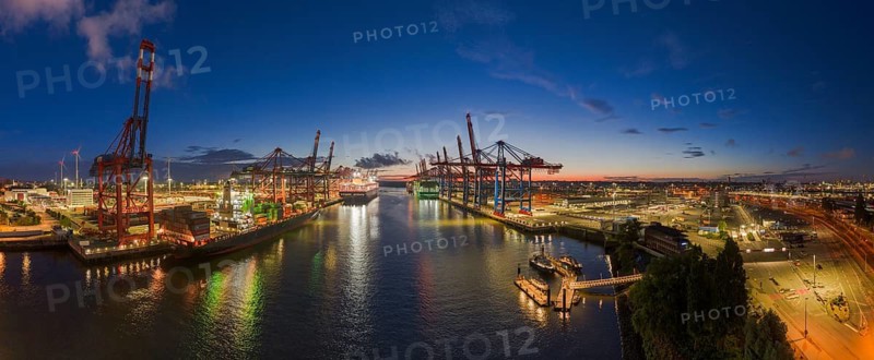 Panoramic aerial view at Waltershof harbour during the Blue Hour with Eurogate Container Terminal Hamburg (CTH) and Container Terminal Burchardkai (CTB) with the brightly lit Ever Meed, Manila Express and Fort Desaix in the background, Hamburg, Germany