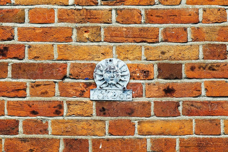 Historic Sun Fire Office fire insurance mark set into a brick wall, once identifying an insured property to the insurance company fire brigade