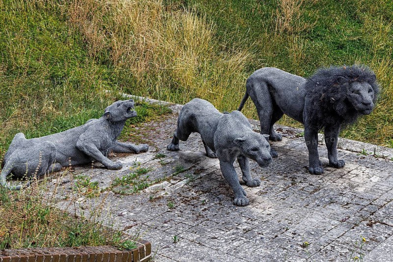 A pride of wire mesh lion sculptures stands on cracked paving within the Tower of London grounds, part of a series of animal artworks marking the site's centuries long history as home to the Royal Menagerie before the collection moved to London Zoo in the nineteenth century, London, England, United Kingdom