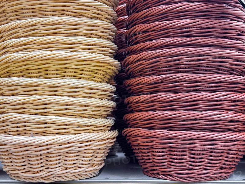 A collection of woven baskets in various colors, including yellow and red. The baskets are stacked neatly, showcasing their intricate designs and textures