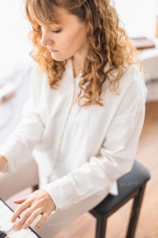 Woman in a white shirt playing the keyboard with intensity and insight