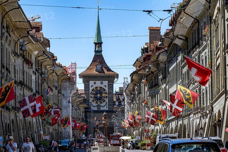 Kramgasse with historic houses decorated with cantonal flags and Swiss national flags, back clock tower Zytglogge, old town, Bern, Canton of Bern, Switzerland