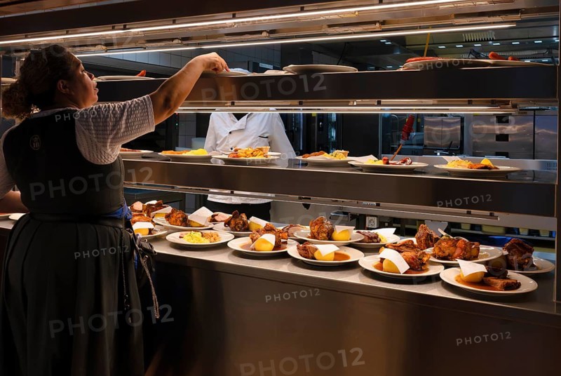 Interior view, from the kitchen, cook, orders placed on counter, dishes such as pork knuckle with dumplings, potato dumplings, schnitzel, sausages, waiting for collection by the waitress, Münchner Hofbräuhaus, Platzl, Brauerei Hofbräu, Munich, Bavaria, Germany