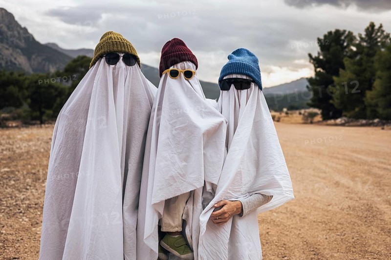 Family dressed as playful ghosts outdoors celebrating Halloween. Creative homemade costumes, seasonal traditions, spooky fun and cozy autumn lifestyle concept with modern holiday aesthetics.