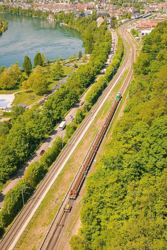 Aerial view of a railway line along a forest next to a river in an urban environment, construction site by Leonhard Weiß for the renovation of the railway station and construction of the overhead line, Waldshut, Germany
