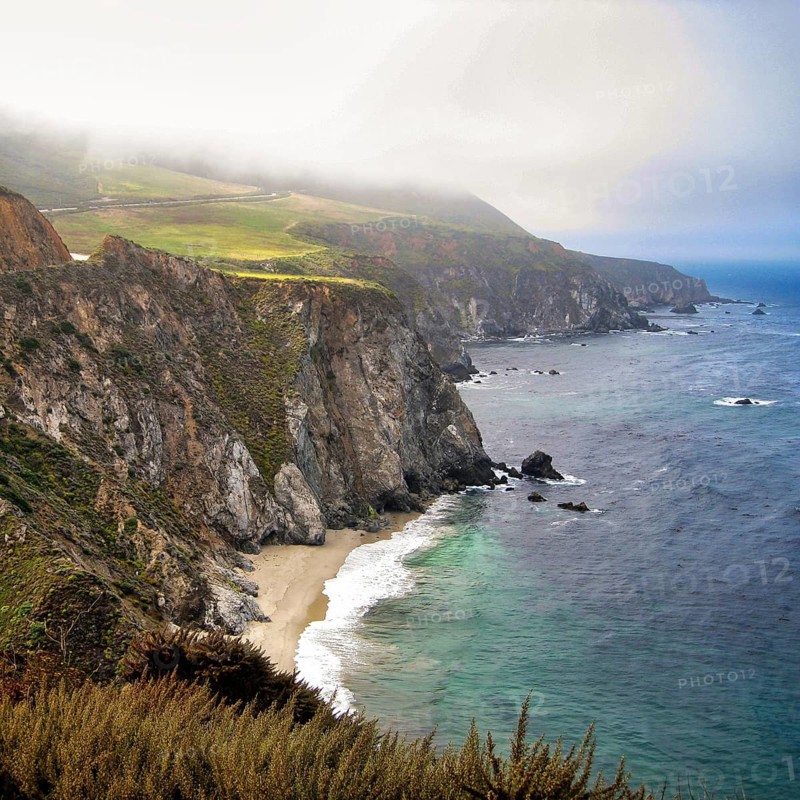 Spectacular coastal scenery of Big Sur along Pacific Coast Highway, California State Route 1, Highway No. 1, rugged cliffs, rocky shoreline, secluded sandy beach Bixby Creek Beach, coastal fog, panoramic Pacific road, California, USA