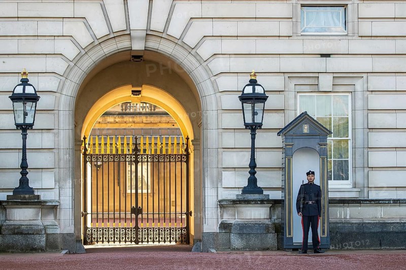 A Queen's Gurkha Signals guardsman stands sentry beside the gilded gate arch of Buckingham Palace, London, England, United Kingdom