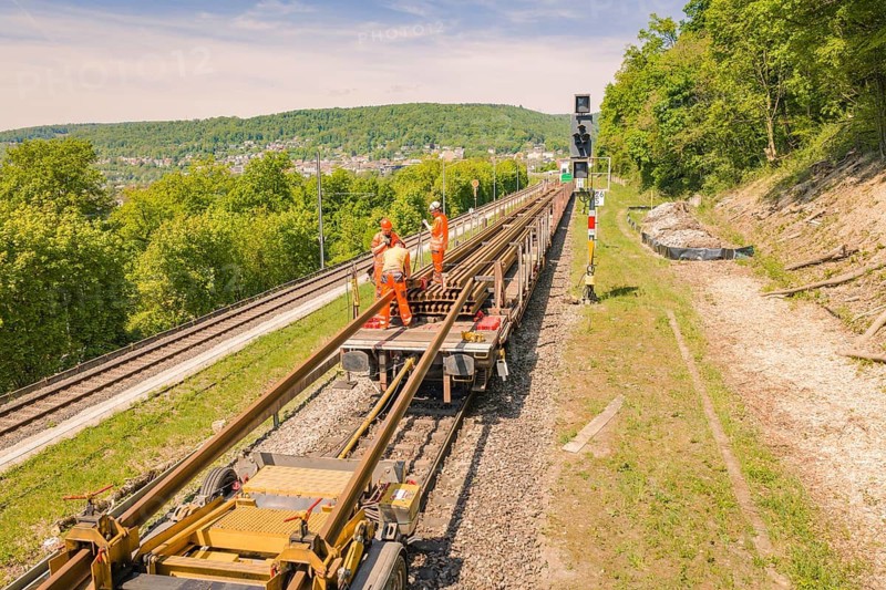 Worker on a rail maintenance platform in a rural area with forest and sky, Leonhard Weiss construction site for the renovation of the railway station and construction of the overhead line, Waldshut, Germany