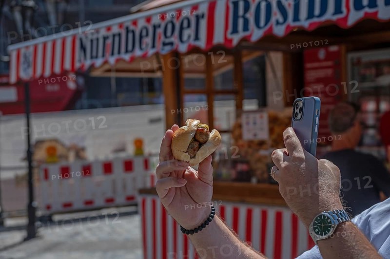 Tourist photographs Nuremberg bratwurst in a roll with his mobile phone, Nuremberg, Middle Franconia Bavaria, Germany