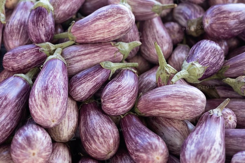 A pile of fresh striped purple eggplants on display at the market