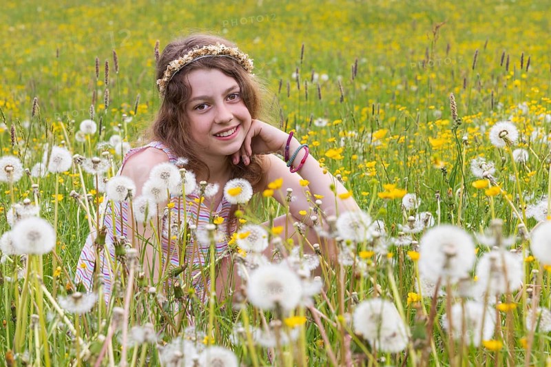 Portrait of a smiling girl sitting in a flower meadow, Mondsee, Salzkammergut, Austria