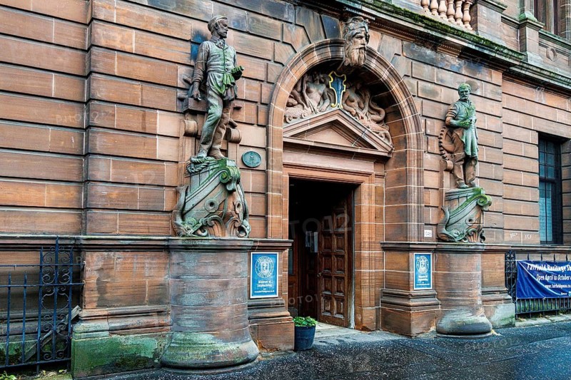 Carved sandstone entrance with statues of a mariner and shipwright beneath a Neptune pediment, Fairfield Heritage Centre, Govan, Glasgow, Scotland, United Kingdom