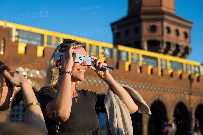 People wearing goggles watch the solar eclipse just in front of sunset on the Oberbaum Bridge in Berlin Friedrichshain on 12/08/2026