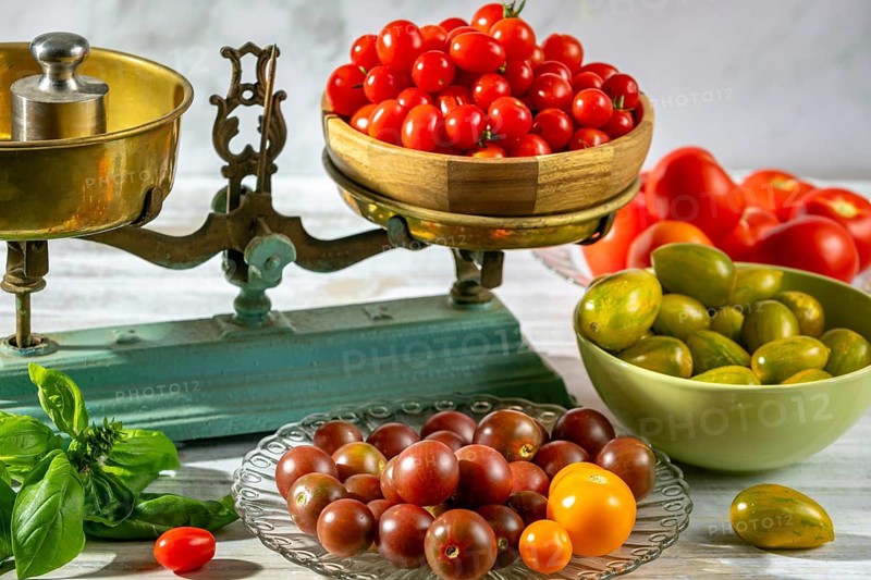 Fresh tomatoes decoratively arranged on and around old scales, natural lighting