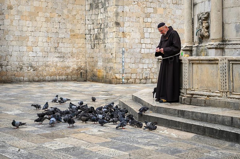 Friar Nedjeljko Jerkan feeds the pigeons at the large Onofrio Fountain, Dubrovnick, Croatia