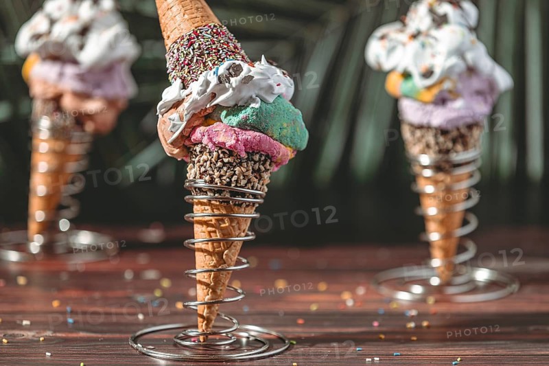 Colorful ice cream in waffles in metal holders decorated with cream and sprinkles