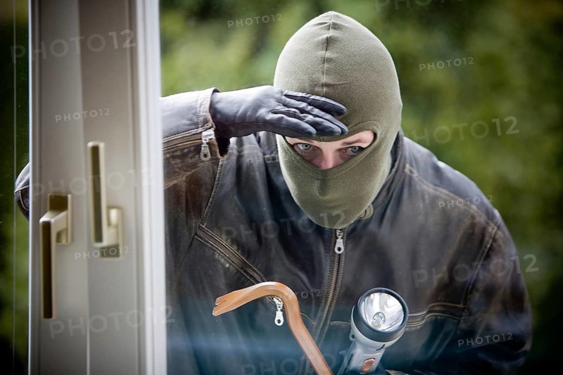 A burglar with a crowbar at a window, studio shot, Austria
