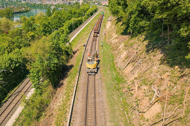 View of a railway line with a work vehicle and trees in natural surroundings, construction site by Leonhard Weiss to renovate the station and build the overhead line, Waldshut, Germany