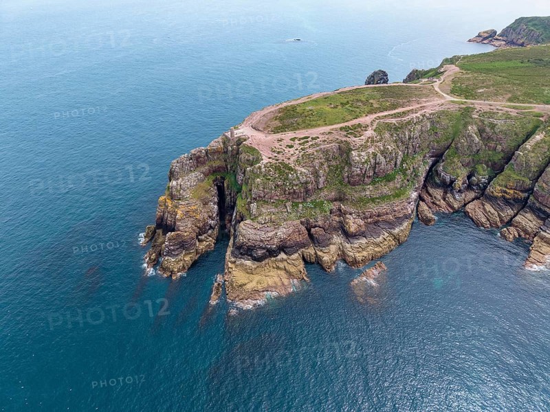 Aerial view of the rocky cliffs at Cap Fréhel with the historic Vauban lighthouse, 17th century Vauban tour, on the heather covered red sandstone cliffs over the Atlantic Ocean, Cap Fréhel, Plévenon, Côtes-d'Armor, Brittany, France