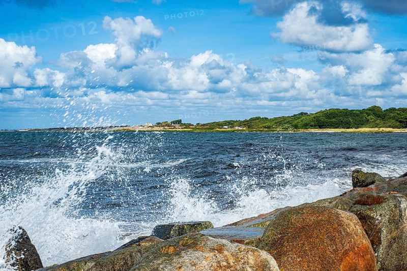 Spray from burning waves splashes across the stone crown of the Torekov pier, Skåne, Sweden. Spray from the Crashing Waves Splashes over the Stone Crest of the Breakwater at Torekov, Scania, Sweden