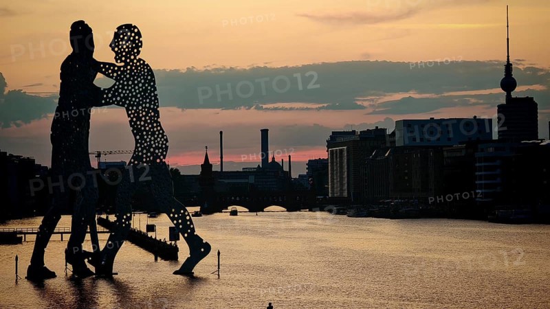 Molecule man, molecule men, sculpture, figures in the water of the Spree against an impressive evening sky and urban environment, sunset, Berlin