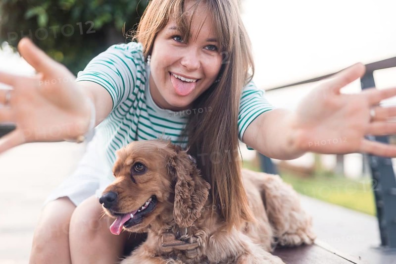 Enthusiastic expression as a woman playfully opens arms with her dog nearby
