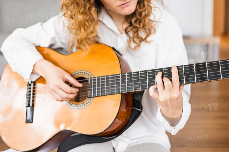 Close-up of a person playing a guitar, focusing on fingers and strings