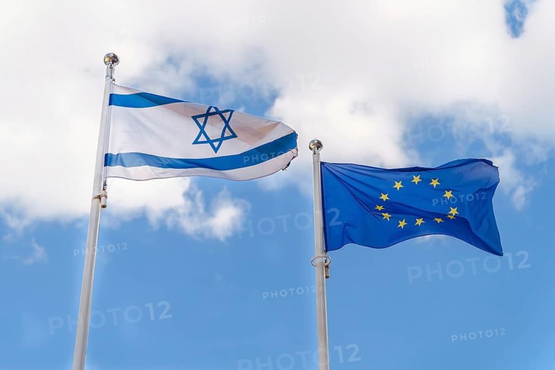 The Israeli flag and the EU flag fly against the sky. Cooperation and mutual support between Israel and the countries of the European Union, Flags of Israel and the European Union against a backdrop of clouds in a blue sky