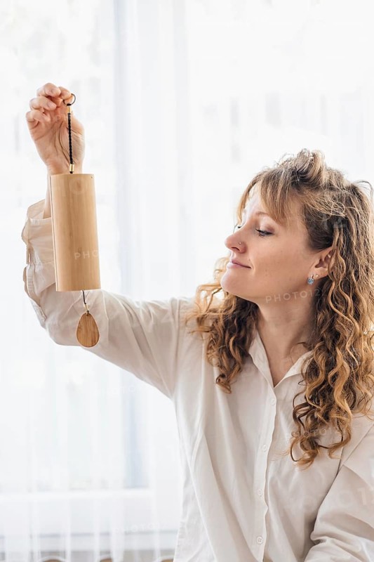 A woman smiling while holding a wooden chime, capturing a positive ambiance