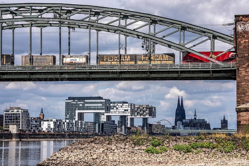 Low water in the Rhine near Cologne, view from the right bank of the Rhine across the Boller Wiesen, heading north, south bridge, railway bridge, freight train, skyline of the city center with the cathedral, inland navigation is severely restricted, only a few ships sail, then with a significantly reduced load, on the day of recording it was the lowest Rhine level ever measured in Cologne, 60 cm, North Rhine-Westphalia, Germany