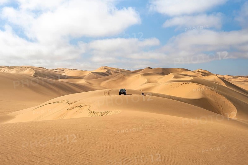 Off-road vehicle between sand dunes, sea of dunes, sandy desert, impressive desert landscape, Namib Naukluft Park, Namib Desert, Namibia