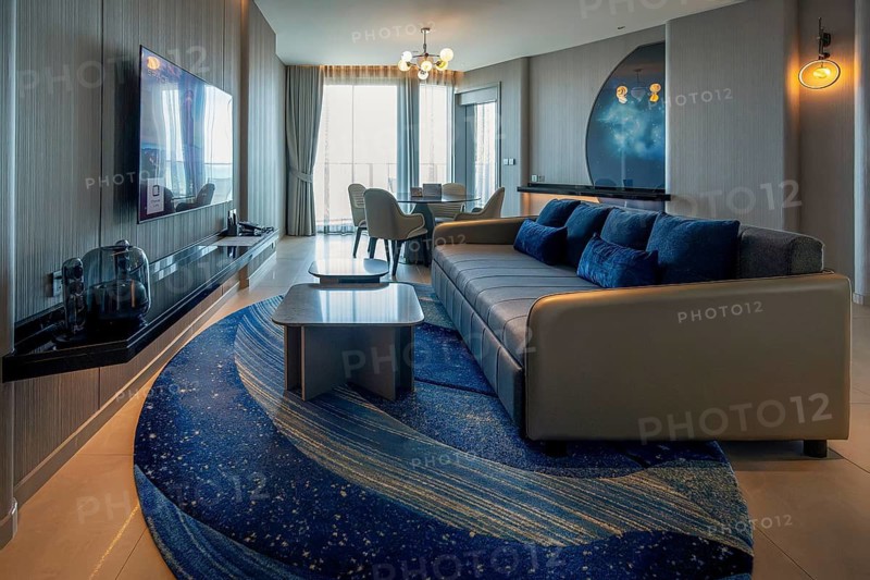 Hotel suite living area with sofa, dining table and XXL television, Pattaya, Thailand