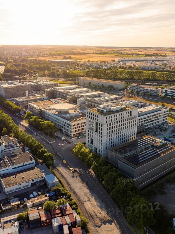 Traffic road and large building complexes in an industrial area at sunset, construction site of the new airfield clinic, Böblingen, Germany