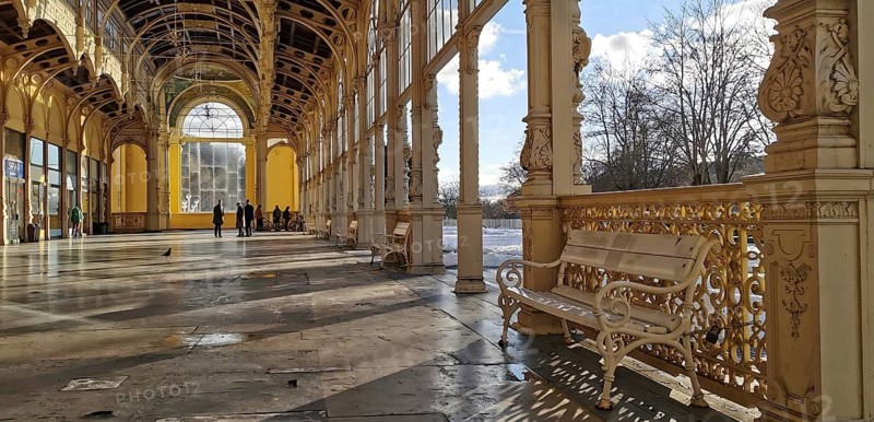 Quiet historic arcades with a bench that stands in the sun. Elegant railing, Maxim Gorky Kollonade, Marianske Lazne main collonade, Marienbad, Czech Republic