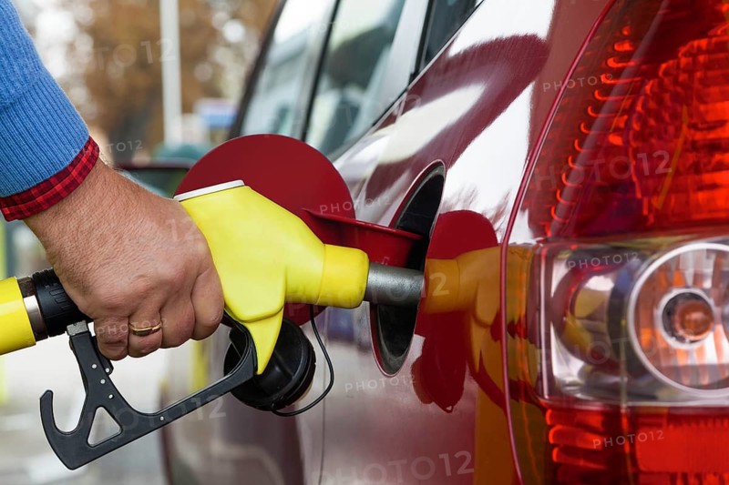 A young woman tank of gas at a gas station. Car costs are becoming more and more expensive due to gas prices