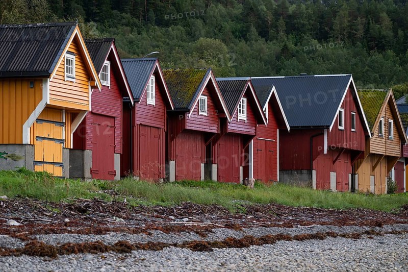 Red and yellow boathouses on a rocky beach, near Ålesund or Alesund, Møre og Romsdal Fylke, Norway