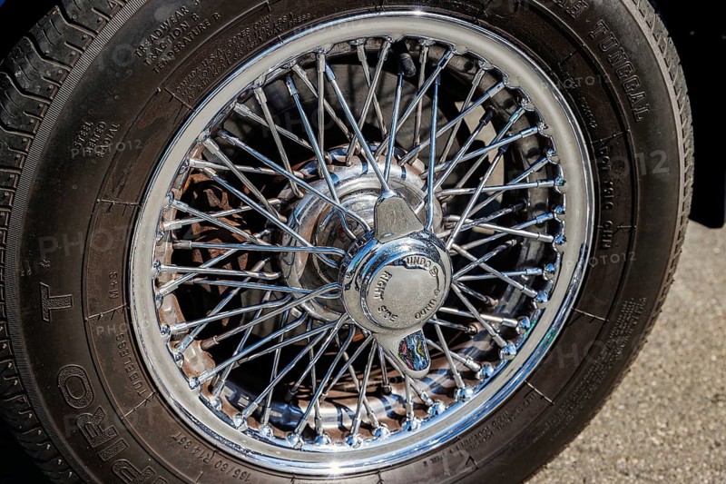 Chrome wire wheel and knock-off spinner hub of a classic MG sports car at a car meet