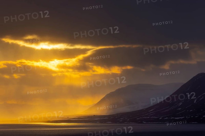 Isfjorden, Isfjord showing midnight sun at sunset with dark rain clouds in spring, Spitsbergen, Svalbard, Norway