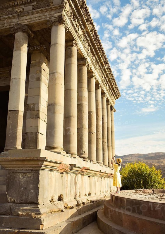 Young tourist woman taking picture in Armenia by Garni roman temple on summer vacation - Travel, holidays and European landmarks concept. Blogger travels world capture landmarks. Unesco sites Armenia