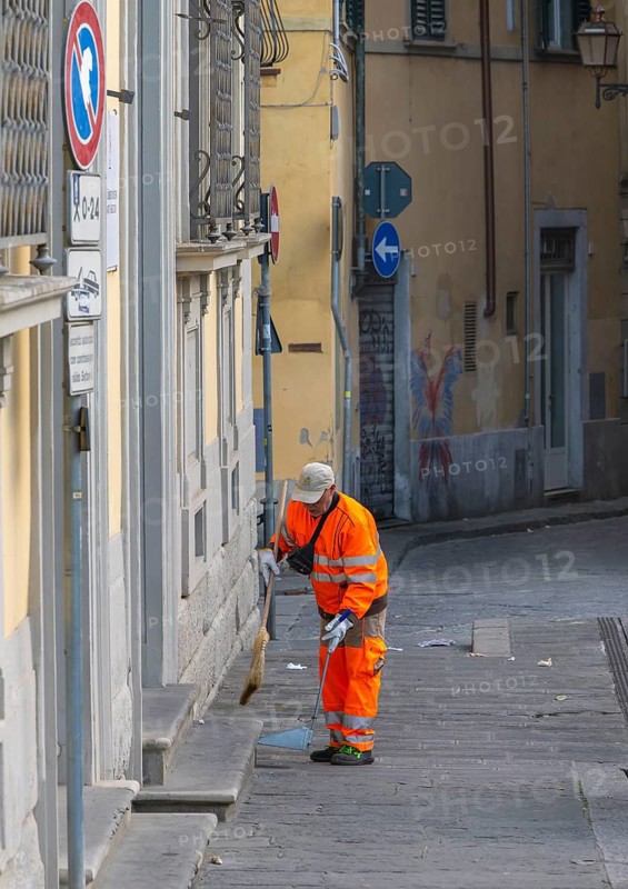 City cleaning workers wearing orange-colored protective clothing working in the city in the morning, Florence, Italy