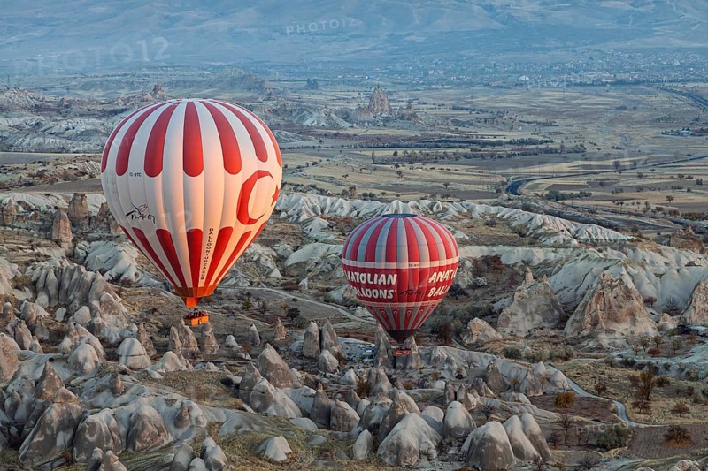 Two colorful hot air balloons float over spectacular valleys and mountains in Cappadocia in an aerial view, Turkey