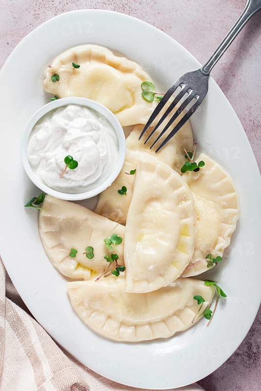 Traditional Georgian kvari dumplings, served with sour cream and herbs, close-up view, no people